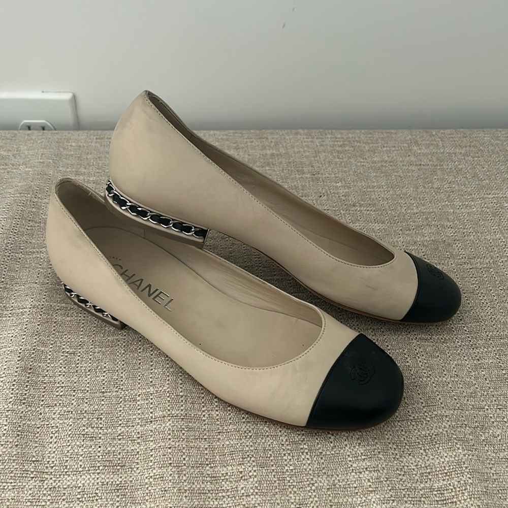 beige Chanel flats with black cap toe and silver hardware